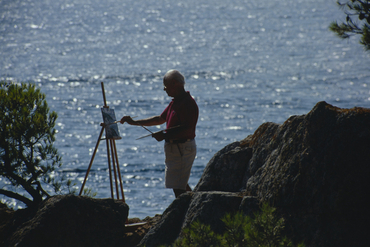 Artista pintant al costat del mar