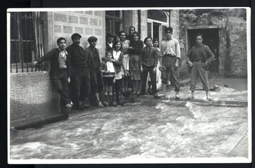 Inundació de Banyoles a causa del desbordament de l'estany. Habitants posant per a la fotografia a la plaça de la Font inundada