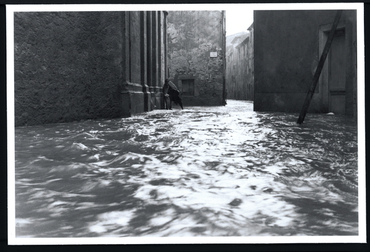 Inundació de Banyoles a causa del desbordament de l'estany. Home caminant recolzant-se a les parets de l'església de Santa Maria dels Turers
