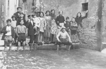 Inundació de Banyoles a causa del desbordament de l'estany. Habitants sobre taulons de fusta, en un carrer inundat