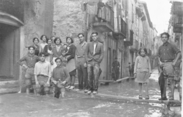 Inundació de Banyoles a causa del desbordament de l'estany. Carrer Major inundat amb habitants sobre taulons de fusta